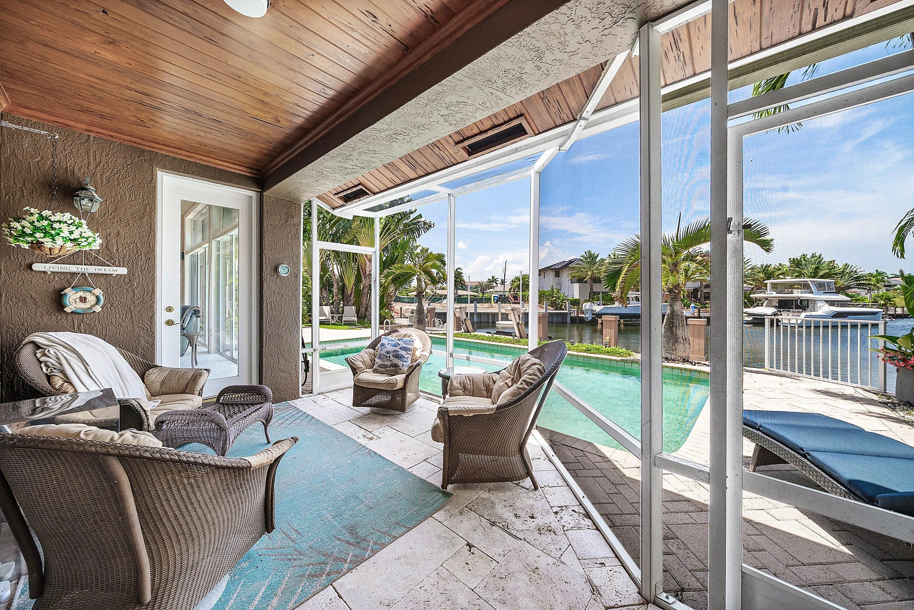 Screened lanai featuring a wood-finish tongue-and-groove ceiling, tiled flooring, and direct access to the outdoor pool area