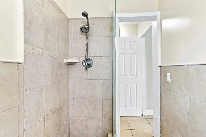 Shower with tiled walls, a multi-function showerhead, and a glass partition