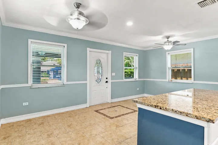 Tiled flooring featuring a decorative inlay, crown molding, and two ceiling fans with integrated lighting