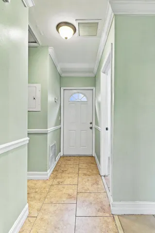 Entryway featuring tile flooring, a white paneled door with an arched glass insert, and crown molding