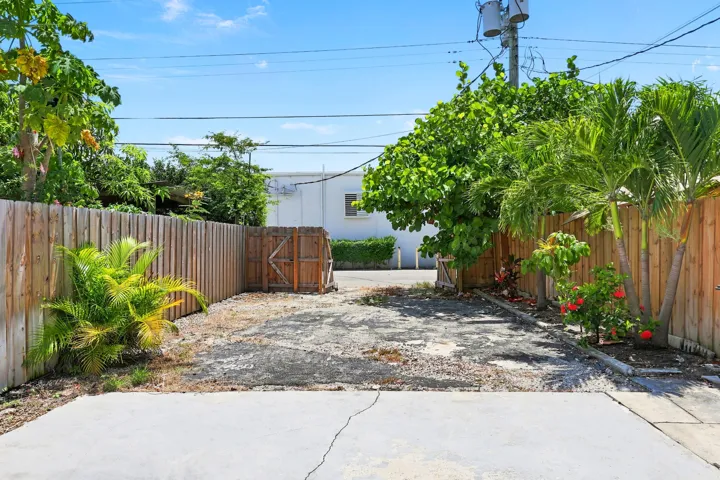 Paved concrete surface with a wood privacy fence and established tropical landscaping