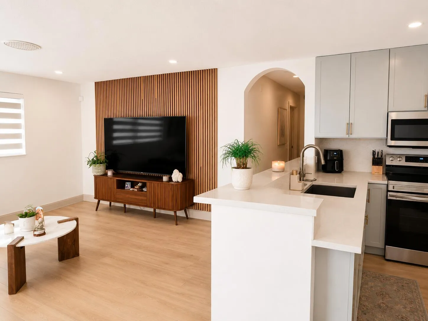 Contemporary kitchen featuring light gray cabinetry, stainless steel appliances, a stainless steel sink with a gooseneck faucet, and light-toned countertops