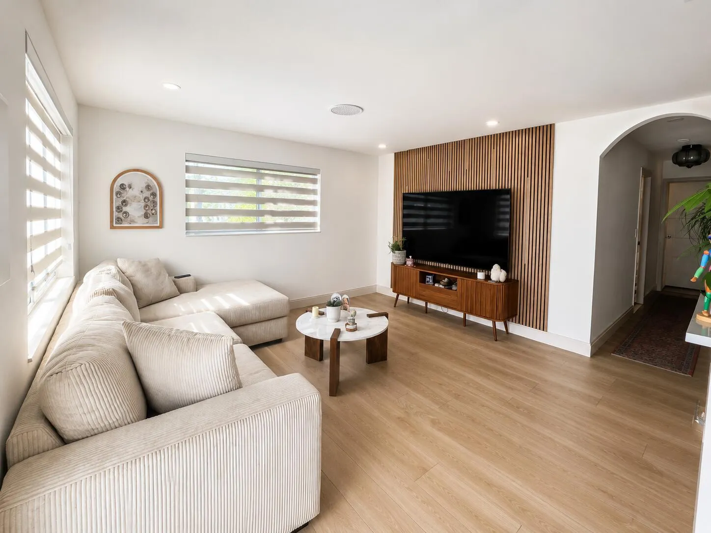 Open-concept living space featuring wood-finish flooring, recessed lighting, and a prominent wood slat accent wall