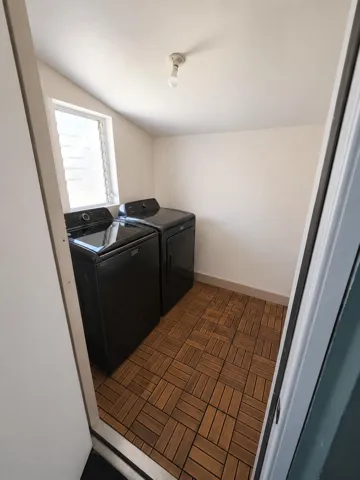 Dedicated laundry area featuring wood-finish tile flooring and a louvered window