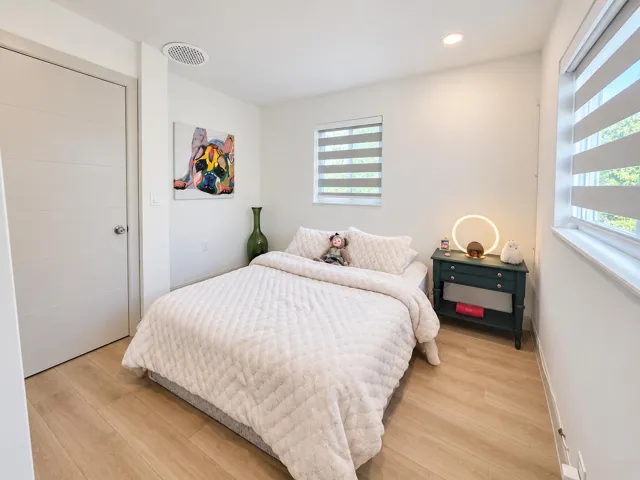 Primary bedroom suite complete with tile floors, ample lighting, and a private en-suite bath featuring vanity, stone countertops, and a modern glass walk-in shower.