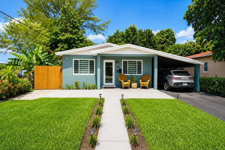 Contemporary exterior with a covered carport, a concrete driveway, a wood fence, a landscaped front yard, and a paved walkway with ground lighting