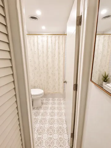 Bathroom featuring patterned floor tiling, a toilet, recessed lighting, and a shower curtain