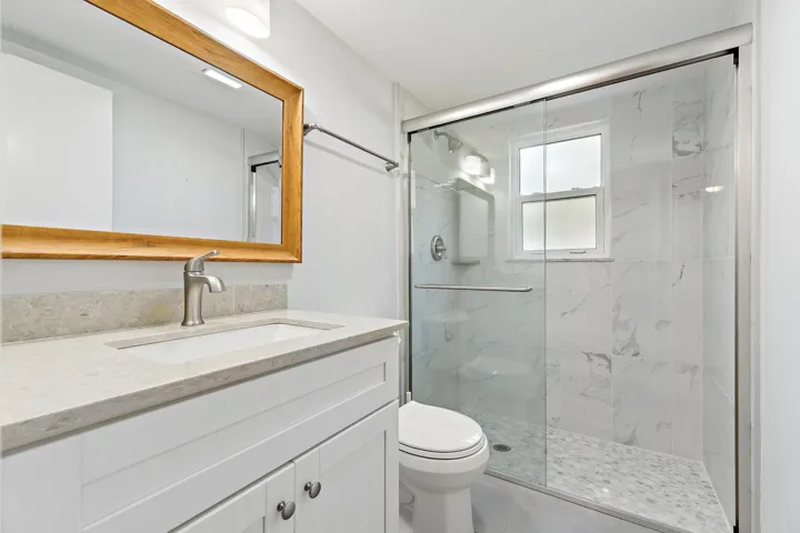 Updated bath with a marble-tiled walk-in shower