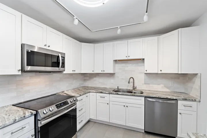 White shaker cabinetry, granite counters, and a stone tile backsplash