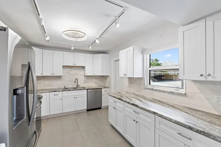 Updated kitchen with white shaker cabinets, stone counters, and stainless steel appliances