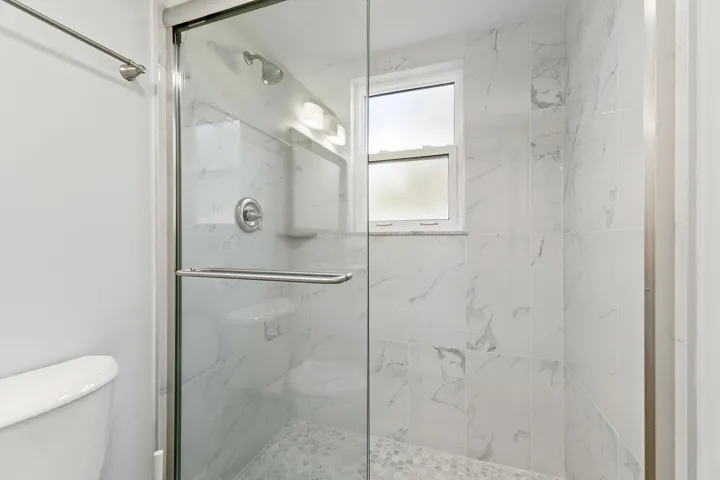 Frameless glass shower with crisp white marble tile