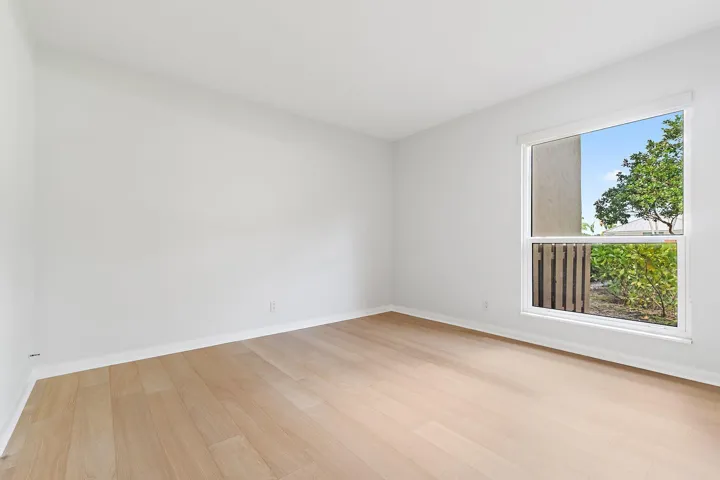Guest bedroom with treetop views and wood-look floors