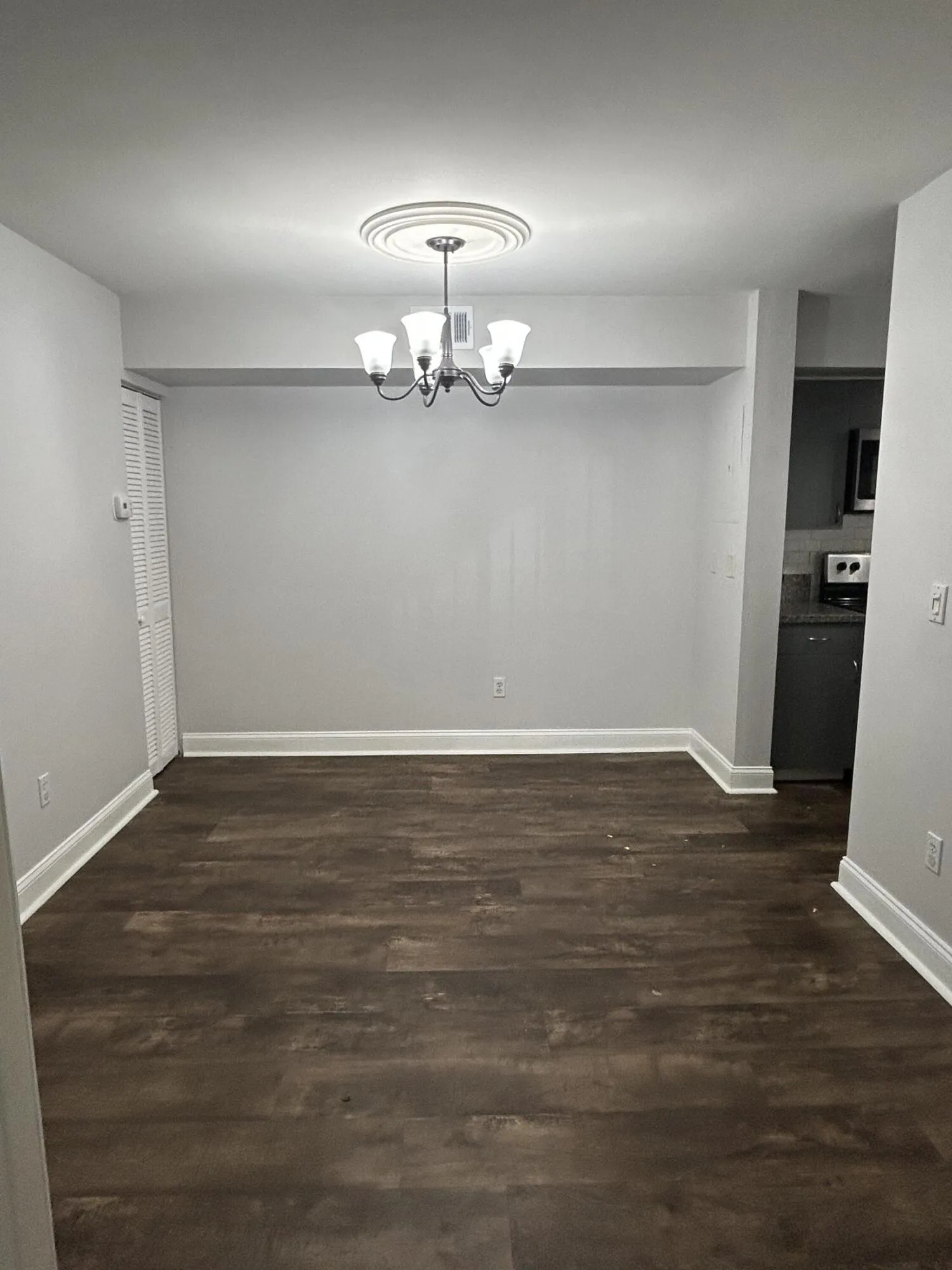 Spacious room featuring wood-finish flooring and a central chandelier with a decorative ceiling medallion