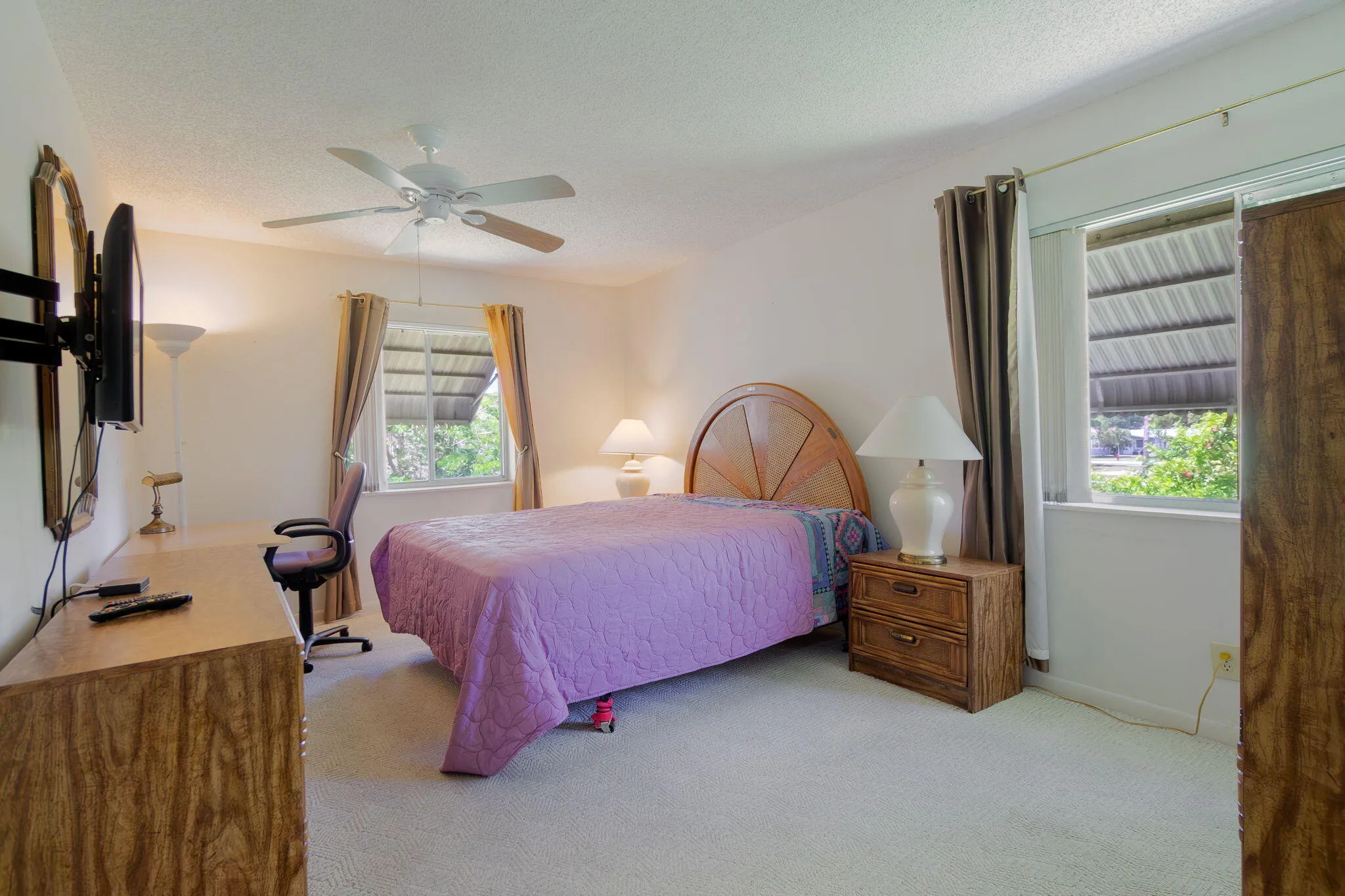Carpeted interior space featuring a ceiling fan with integrated lighting, two windows with window treatments, and a built-in closet with a wood-finish door