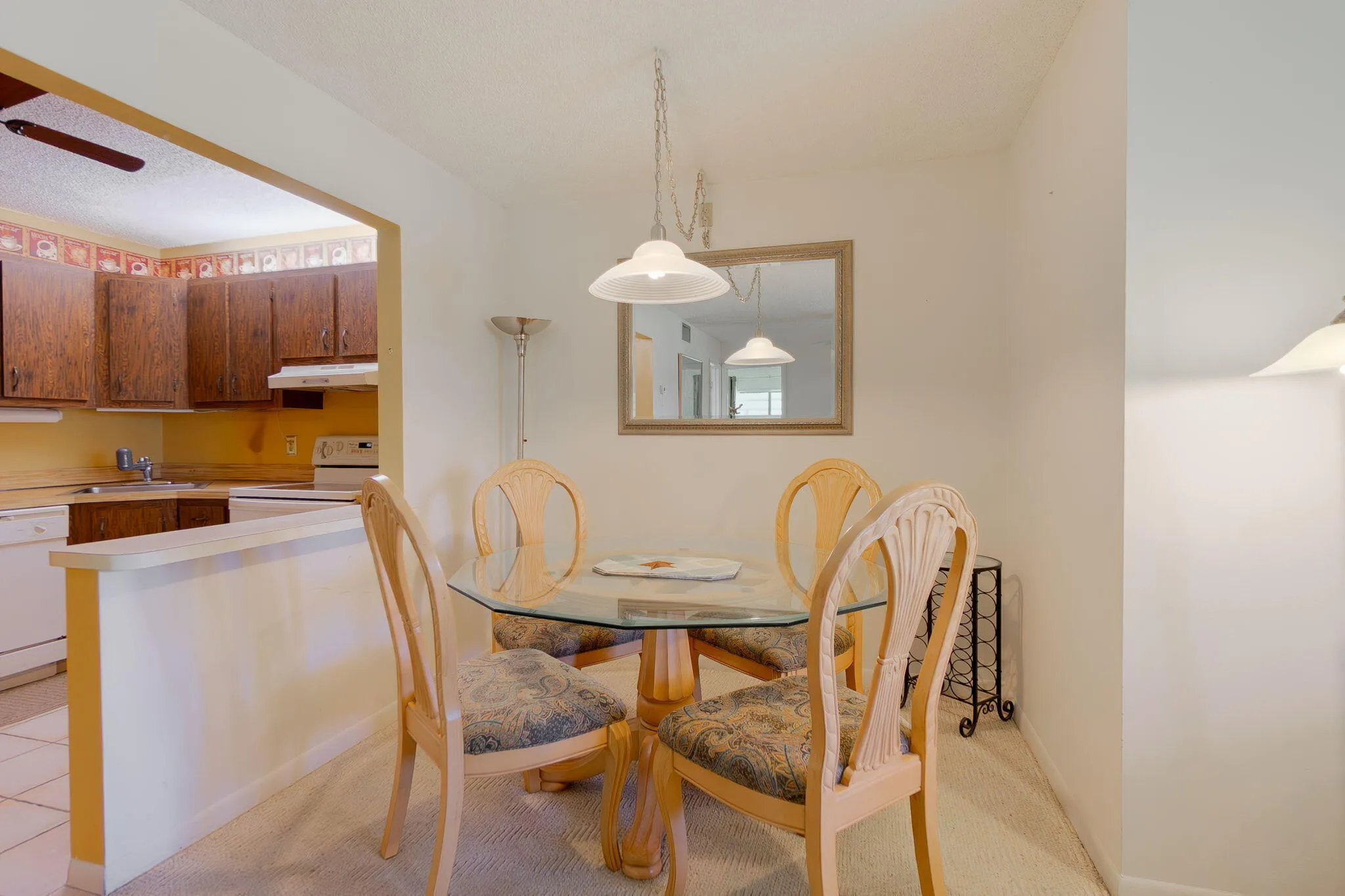 Dining area featuring a glass-top table, suspended pendant light, and a framed mirror