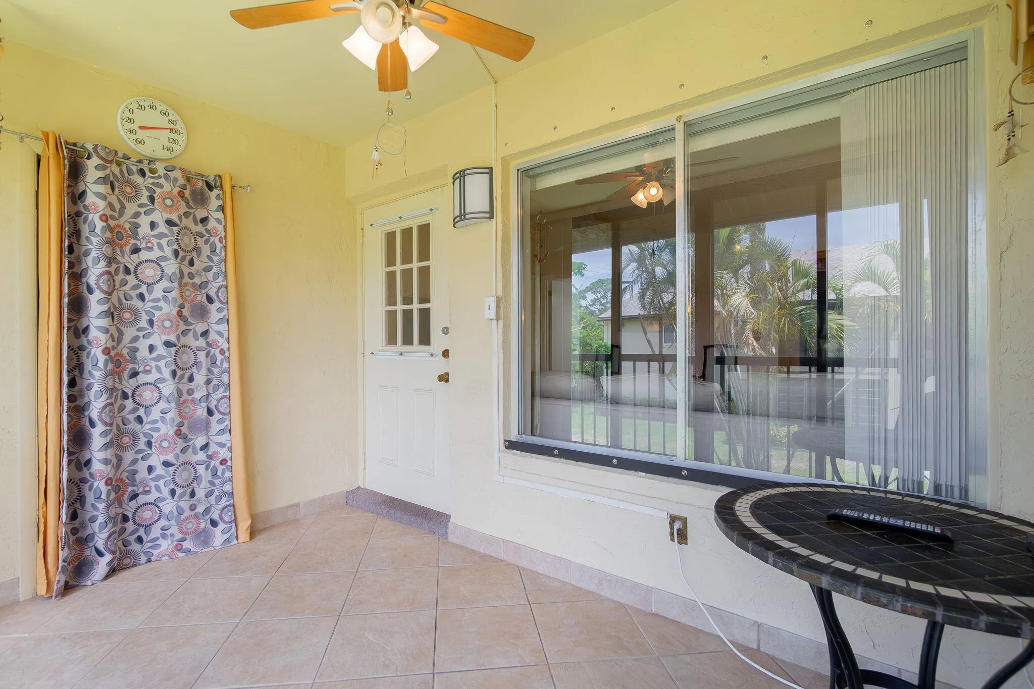 Tiled patio featuring a ceiling fan, sliding glass doors, a multi-pane door, and an exterior wall light fixture