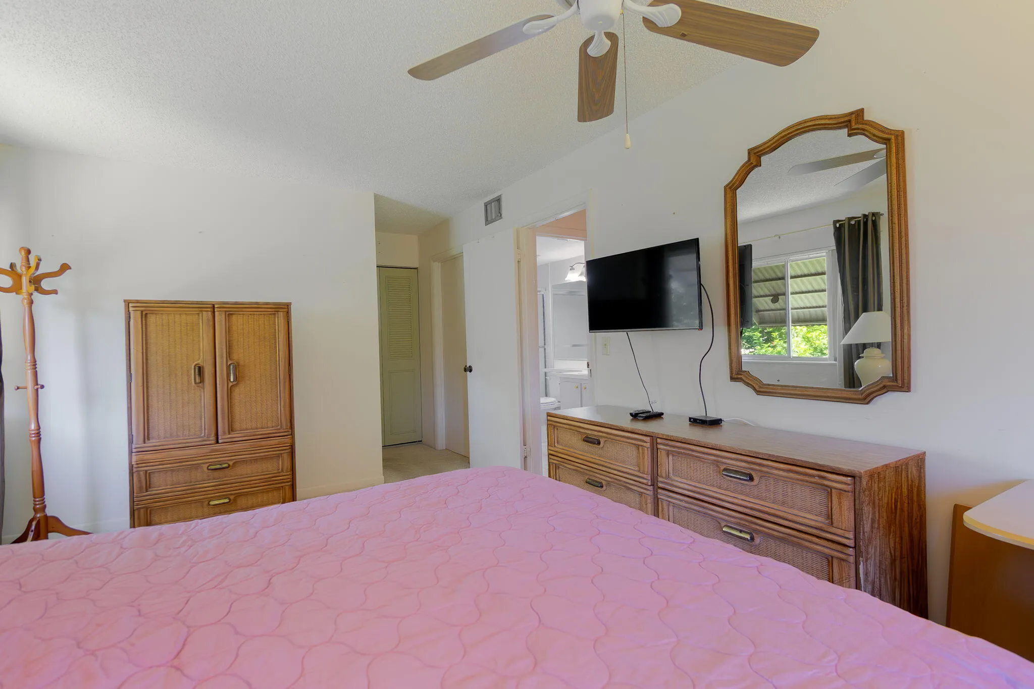 Bedroom featuring a ceiling fan, white walls, and a wood-finish armoire
