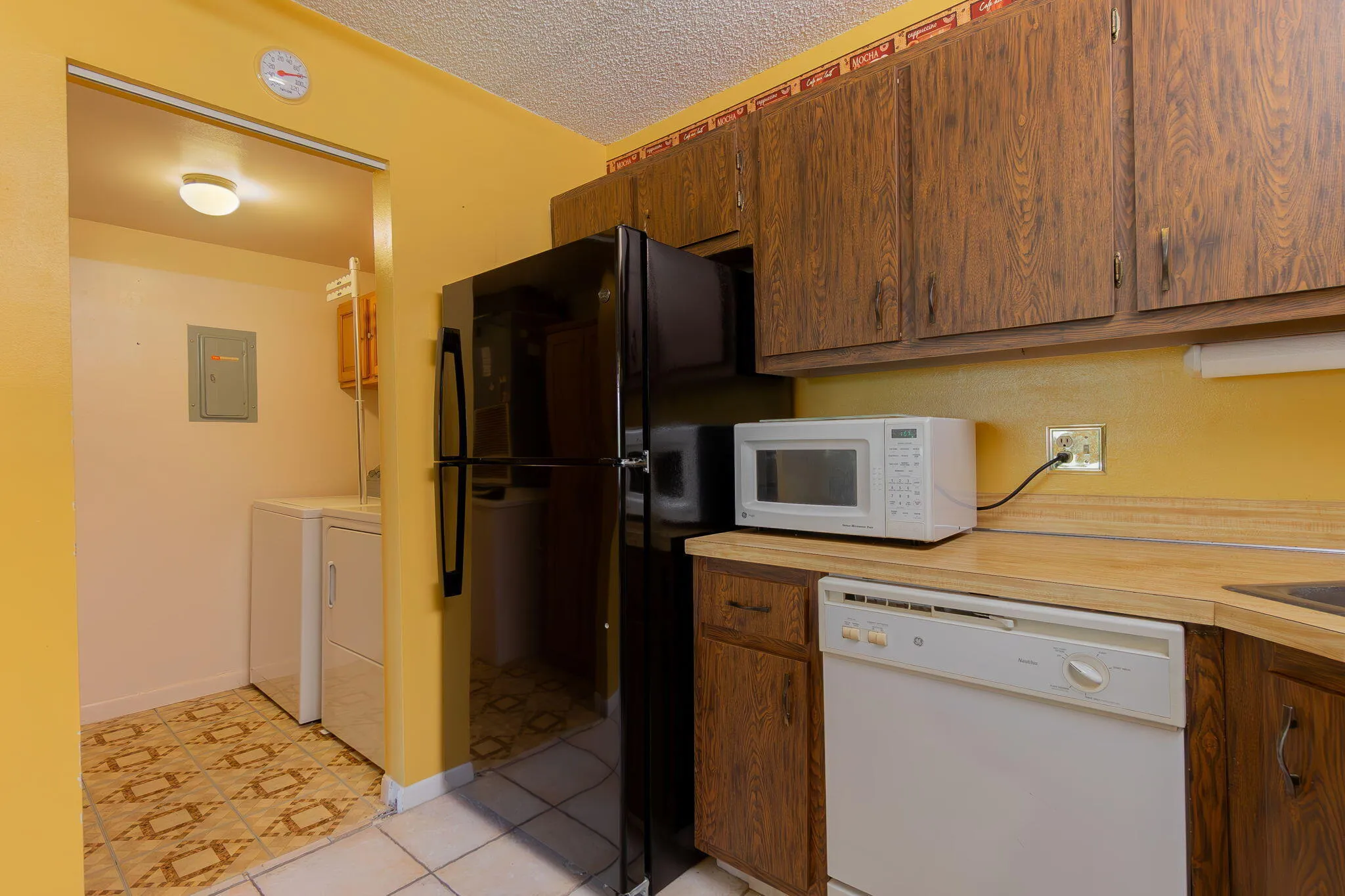 Kitchen featuring wood-finish cabinetry, light-toned countertops, and white tile flooring