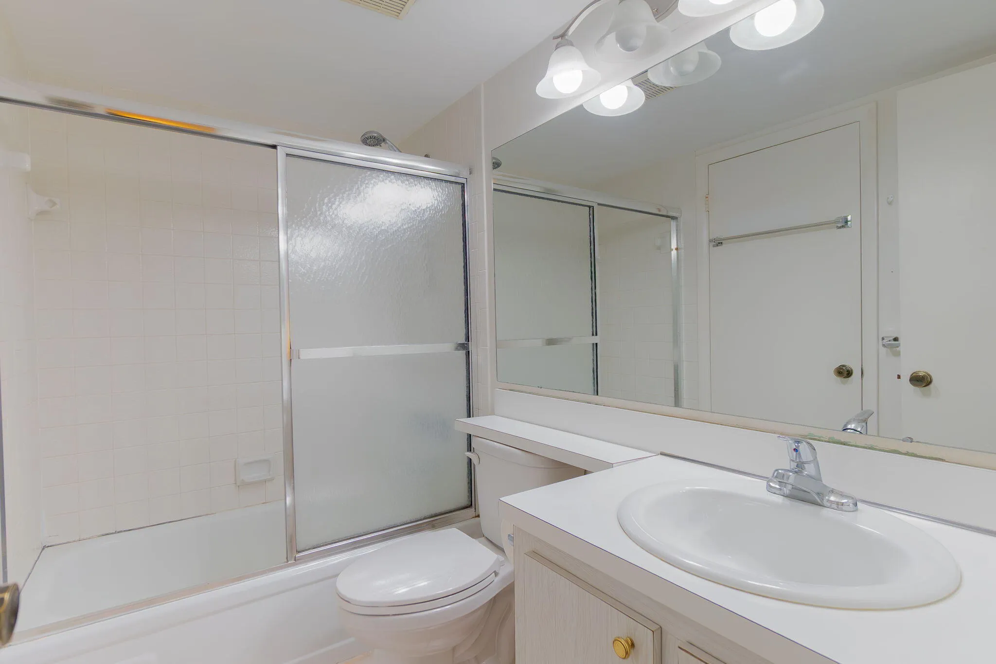 Bathroom featuring a built-in vanity with an oval sink, chrome faucet, and expansive wall mirror