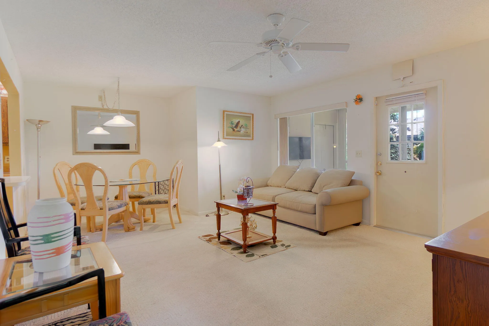 Living area with neutral carpeting and a ceiling fan