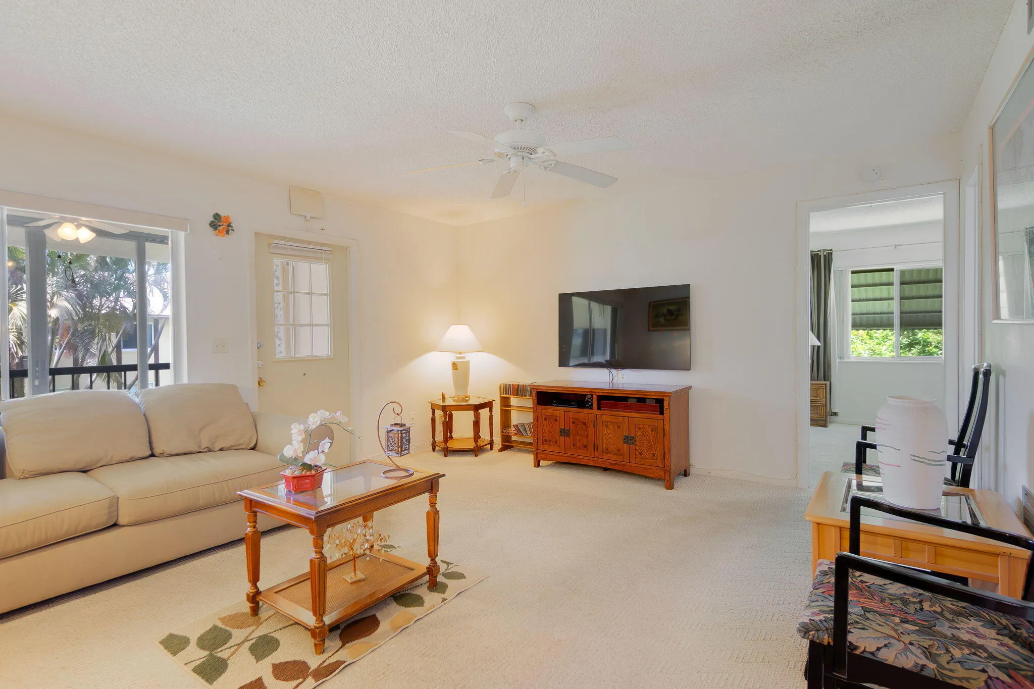 Carpeted living area featuring a ceiling fan, a screened window, and a glass-paneled door