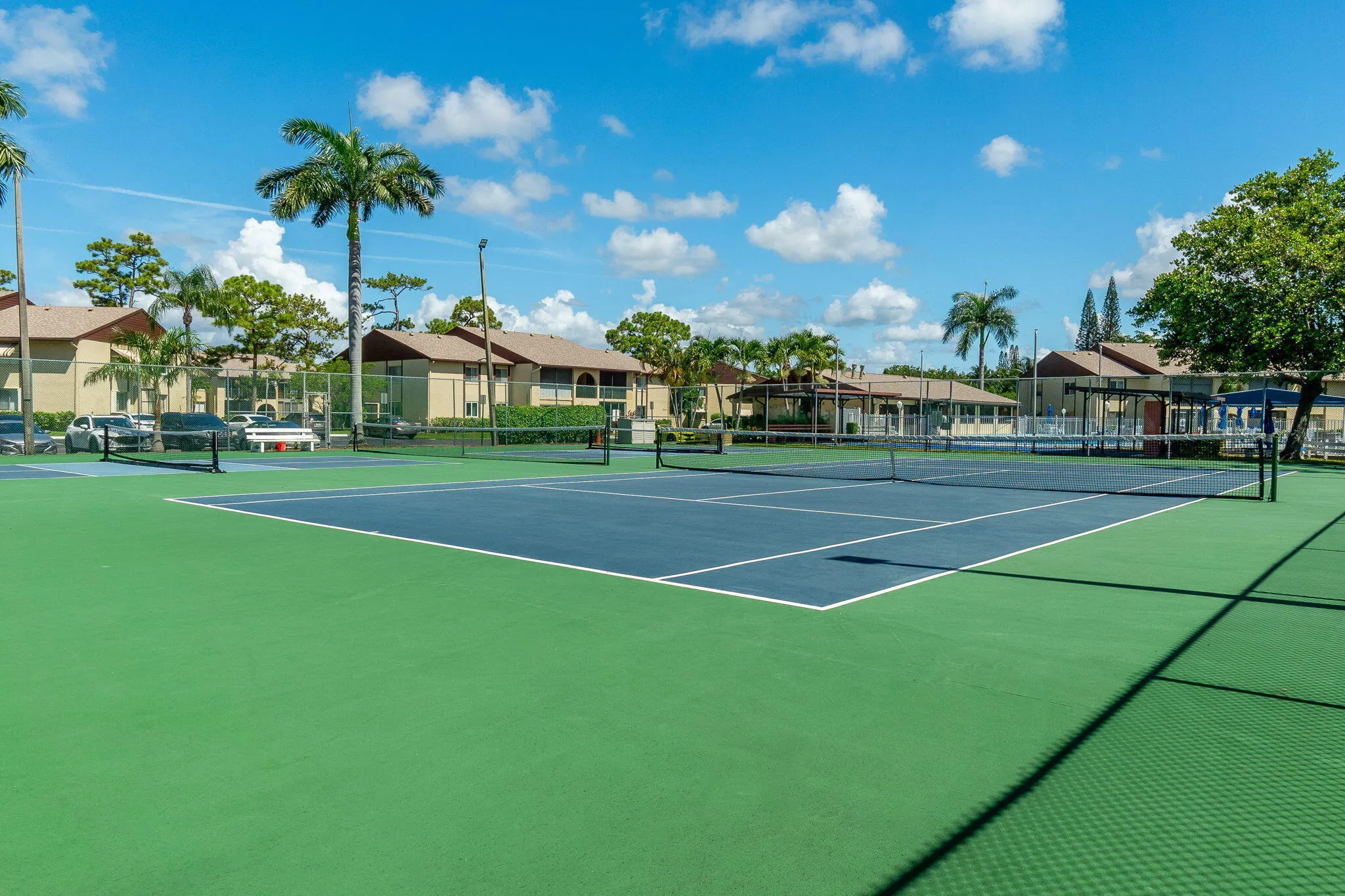 Tennis court with blue and green surfacing, white line markings, and a black net