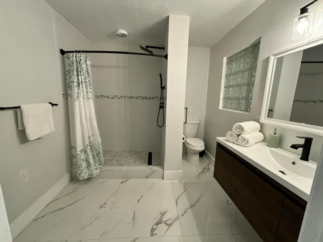 Modern bathroom featuring a floating wood-finish vanity with an integrated sink and matte black fixtures