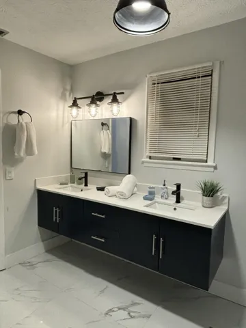 Dual-sink floating vanity with quartz-finish countertop and black hardware