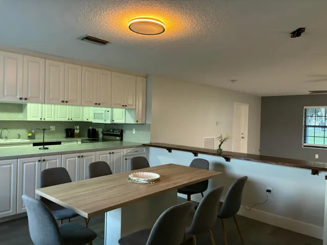 Open-concept kitchen featuring white shaker-style cabinetry, light-toned countertops, and a full-height backsplash