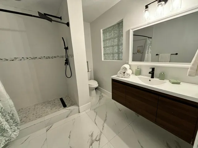 Modern bathroom featuring a floating wood-finish vanity with a white countertop and integrated sink