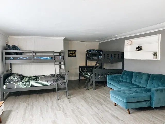 Spacious room featuring wood-finish flooring, white shiplap accent wall, and crown molding