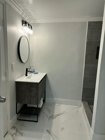 Modern bathroom featuring a floating vanity with integrated sink, black metal frame, and open shelving