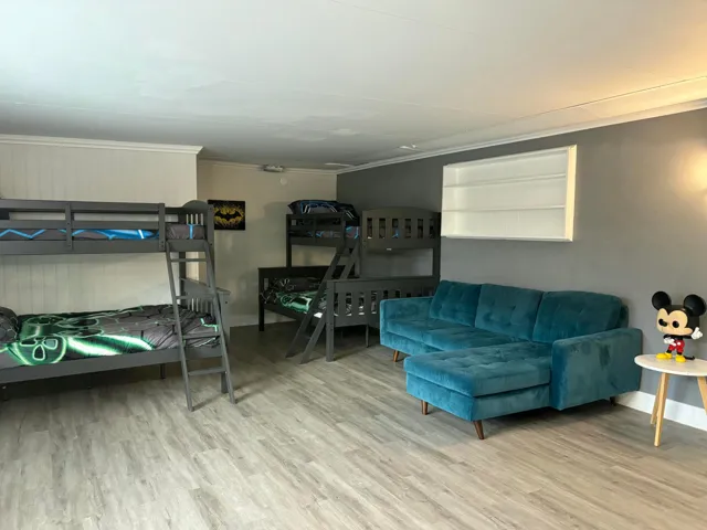 Spacious room featuring light wood-finish flooring, a plush teal sectional sofa, and crown molding