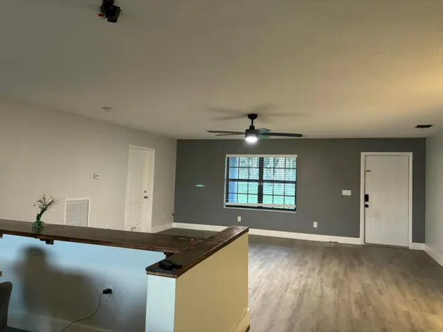 Open-concept interior featuring wood-finish flooring, a ceiling fan with light fixture, and a breakfast bar with a wood-finish countertop