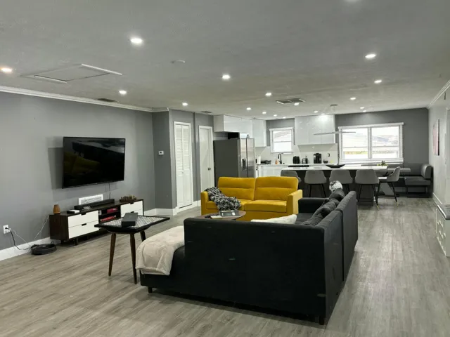 Open-concept living space featuring wood-finish flooring, recessed lighting, and crown molding