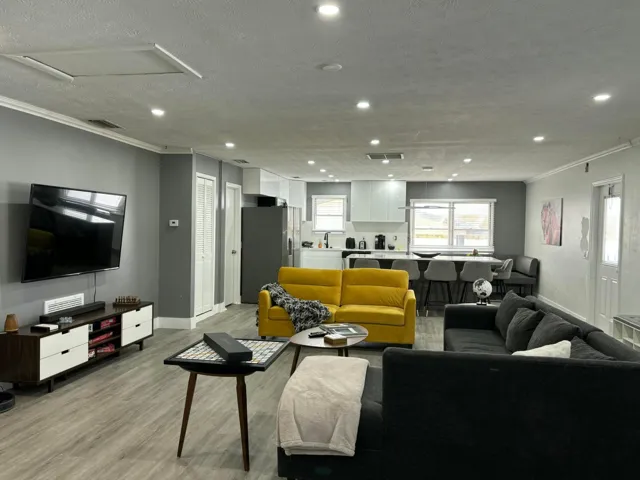 Open-concept living space featuring wood-finish flooring, recessed lighting, and crown molding
