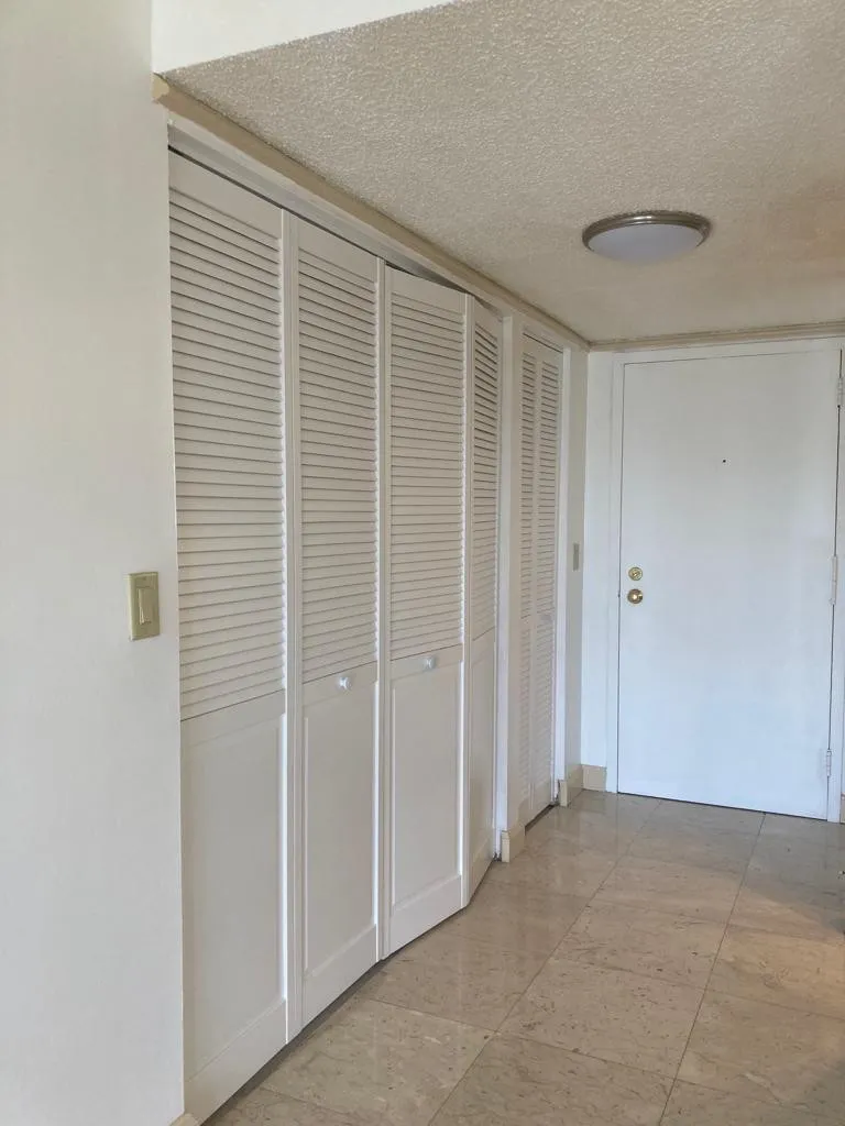 Entryway featuring durable tile flooring and white louvered bi-fold doors providing abundant storage