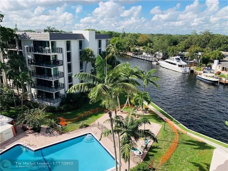 Multi-story building featuring private balconies, a terraced pool deck, and a waterway frontage with docked boats