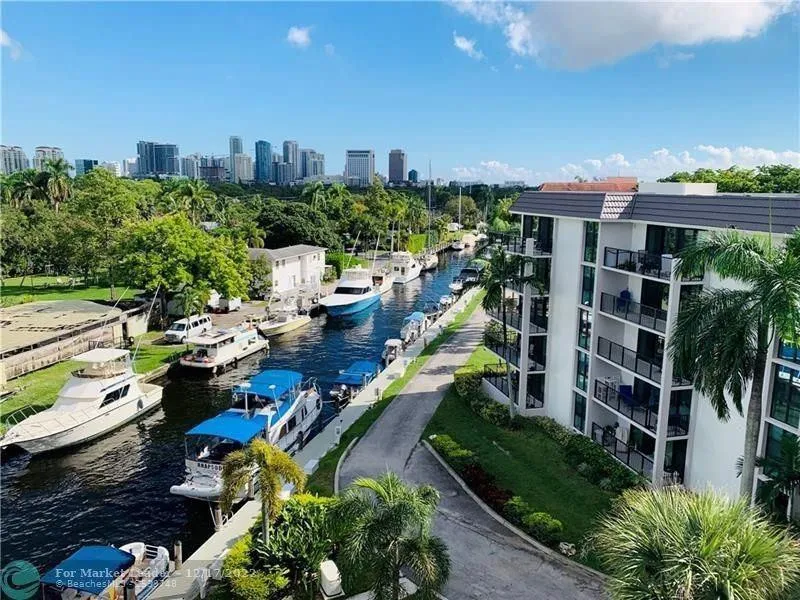 Waterfront condominium building with private balconies and lush tropical landscaping