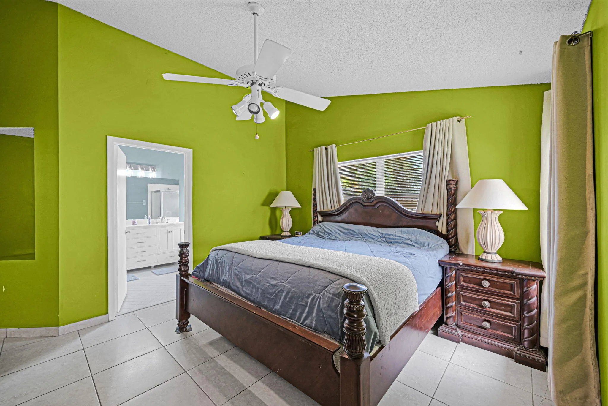 Bright primary bedroom with tile flooring and vibrant green walls