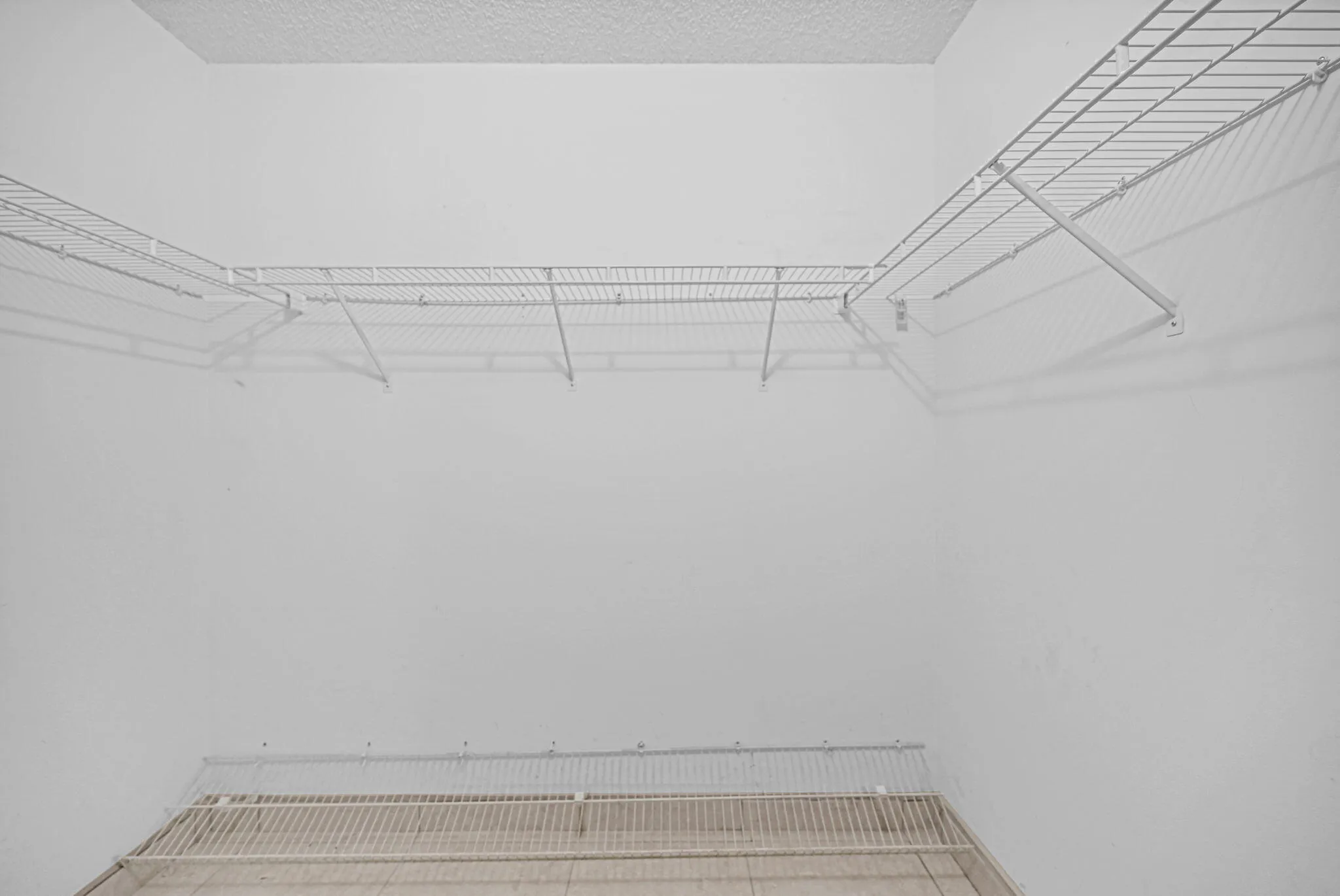 Closet space featuring white wire shelving, a textured ceiling, and a light-colored flooring surface