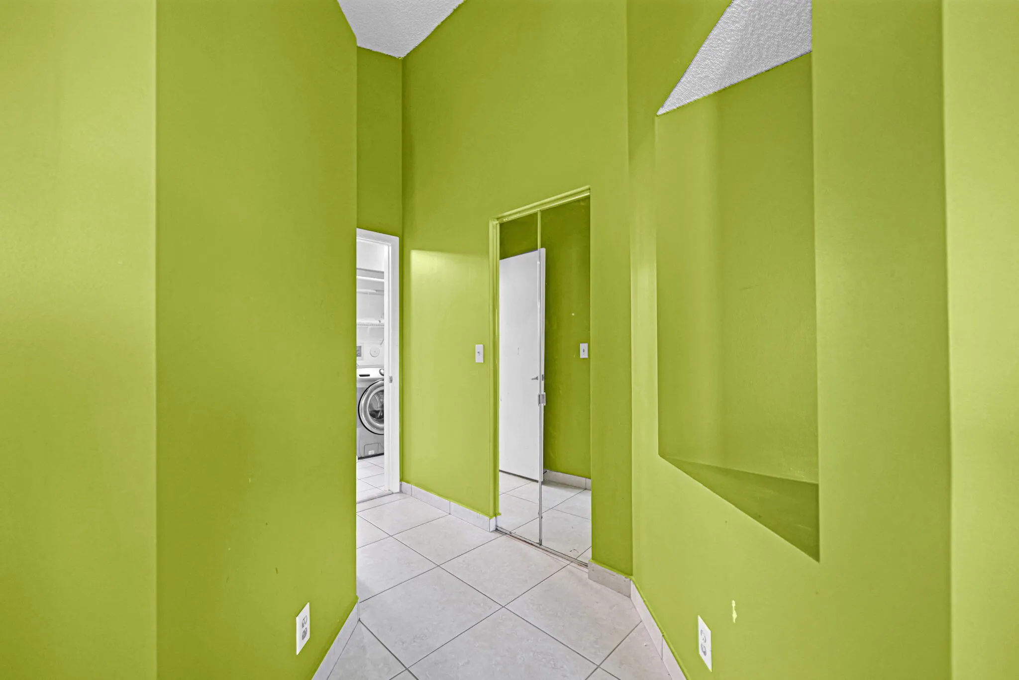 Hallway featuring a built-in niche, light-colored tile flooring, and a mirrored closet door