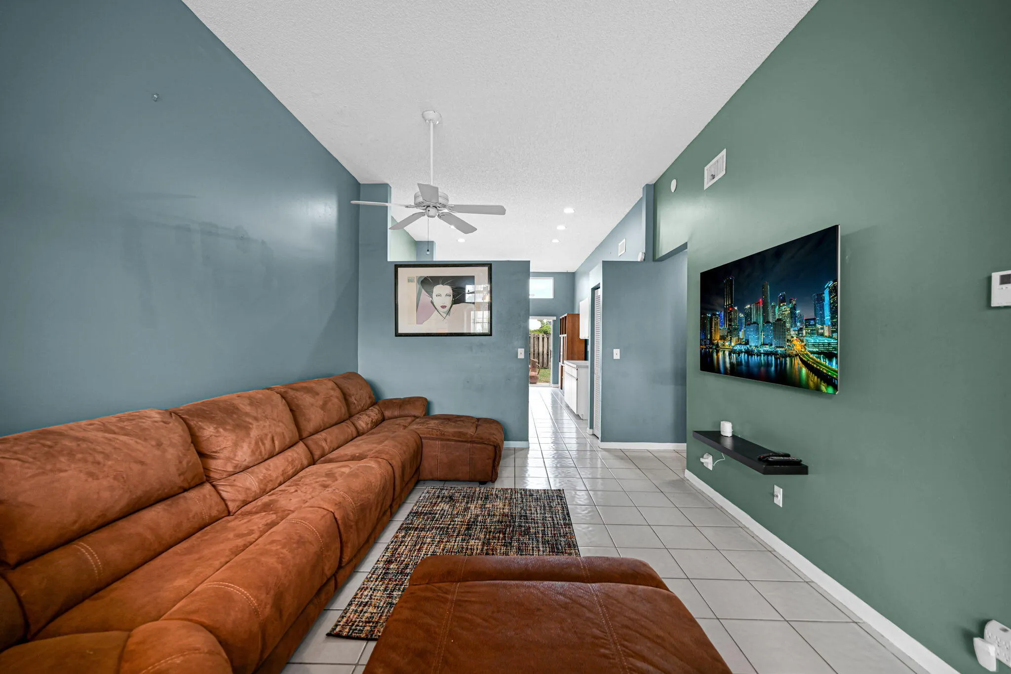 Spacious living area featuring neutral tile flooring, recessed lighting, a ceiling fan, and an integrated wall-mounted media console