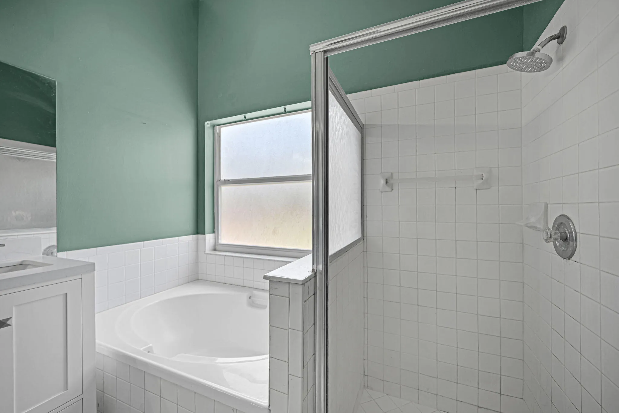 Bathroom with a corner soaking tub, a single vanity with a white countertop, and a separate tiled shower enclosure with a glass door