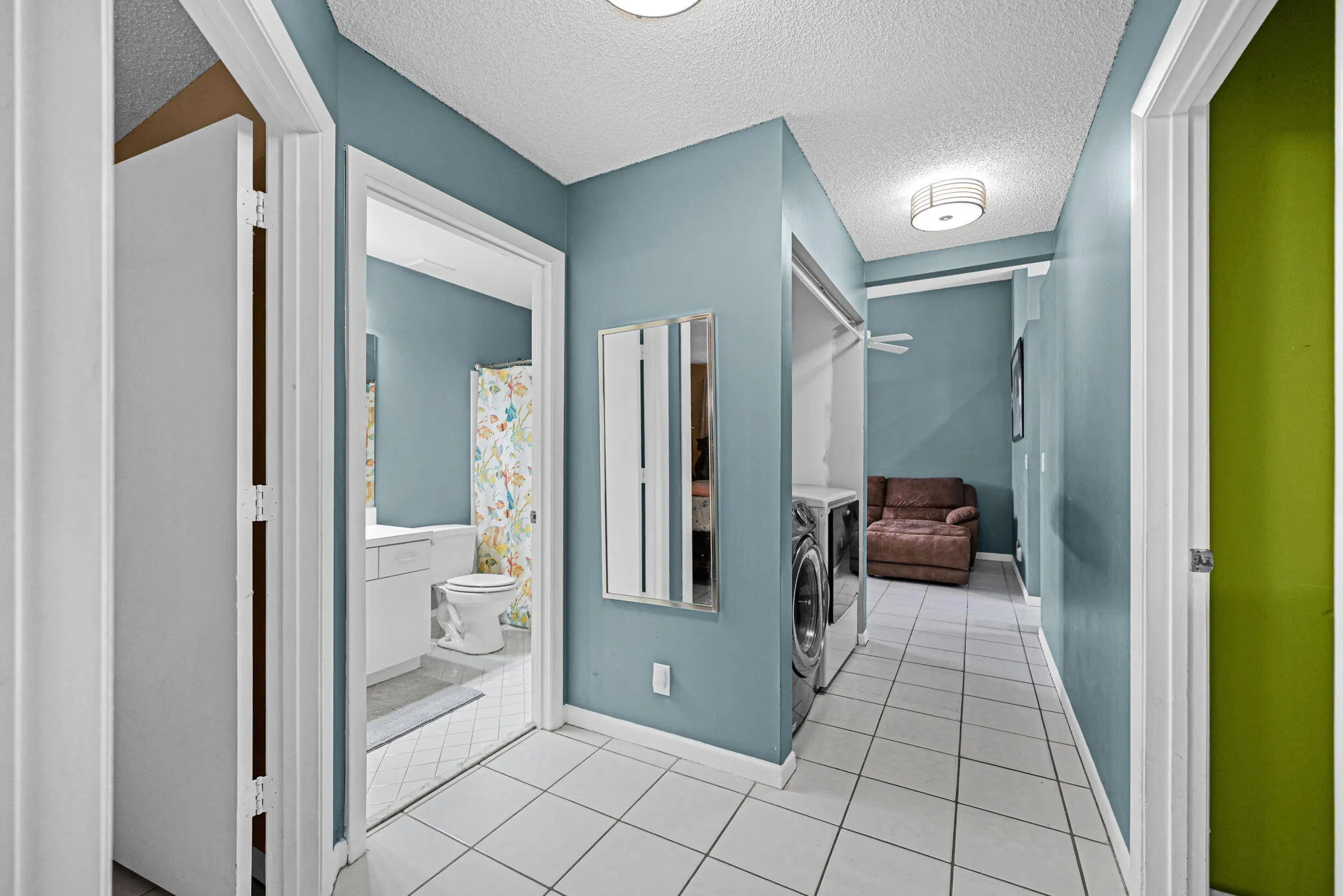 Hallway featuring square tile flooring, built-in laundry area, and neutral wall paint