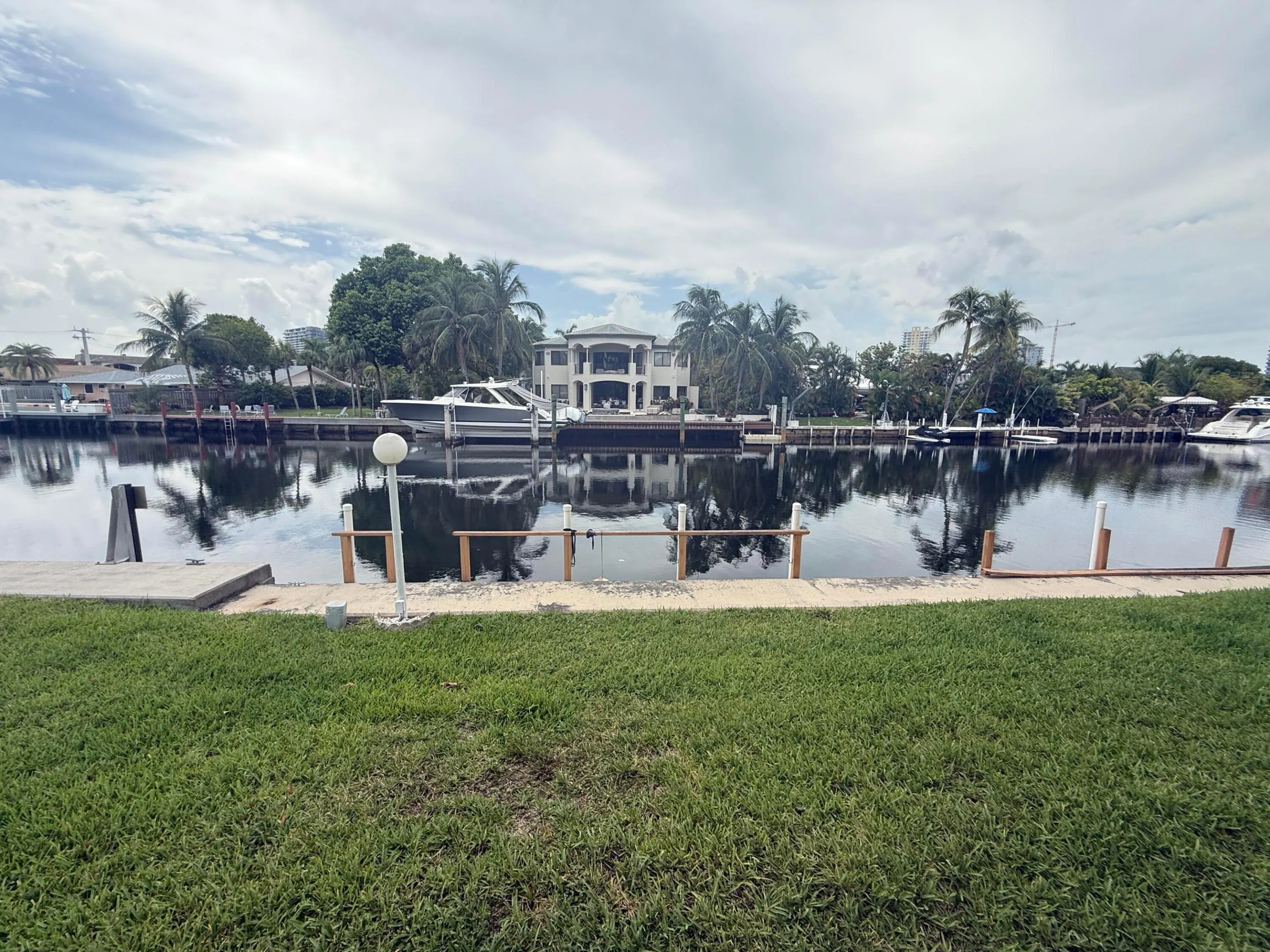 Grassed waterfront property featuring a concrete seawall and dock structure