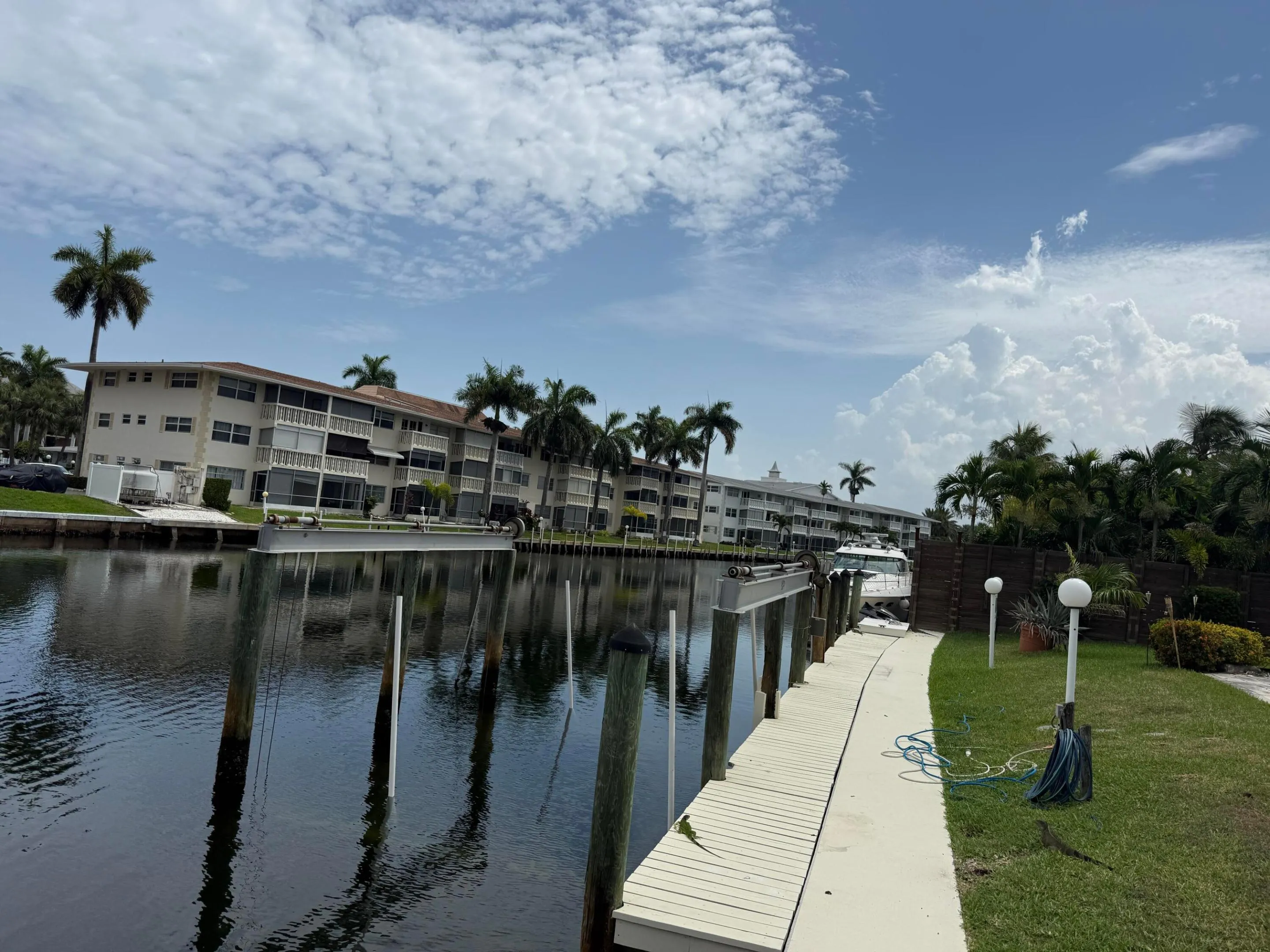 Waterfront property featuring a private dock, green space, and mature palm trees