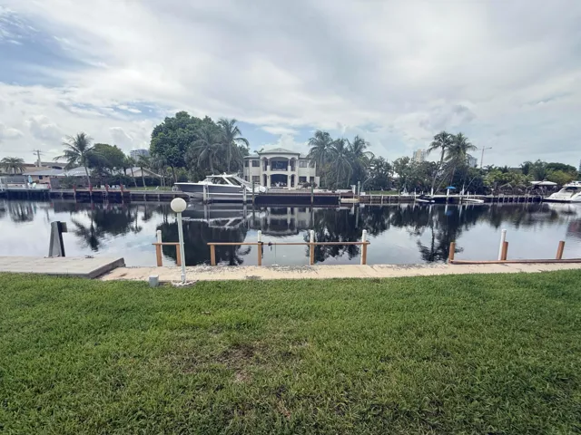 Grassed waterfront property featuring a concrete seawall and dock structure