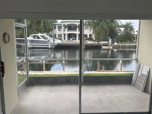 Screened porch with gray tile flooring overlooking the water.