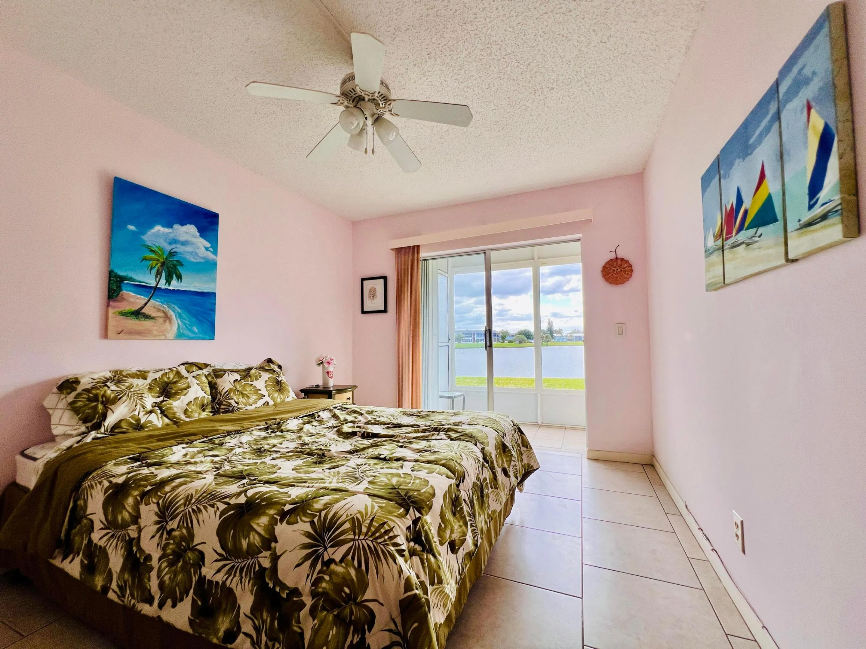 Second of Two Water View Bedrooms. This Bedroom Features A Walk-in Closet, Neutral Tile Flooring, and Access to the Lanai